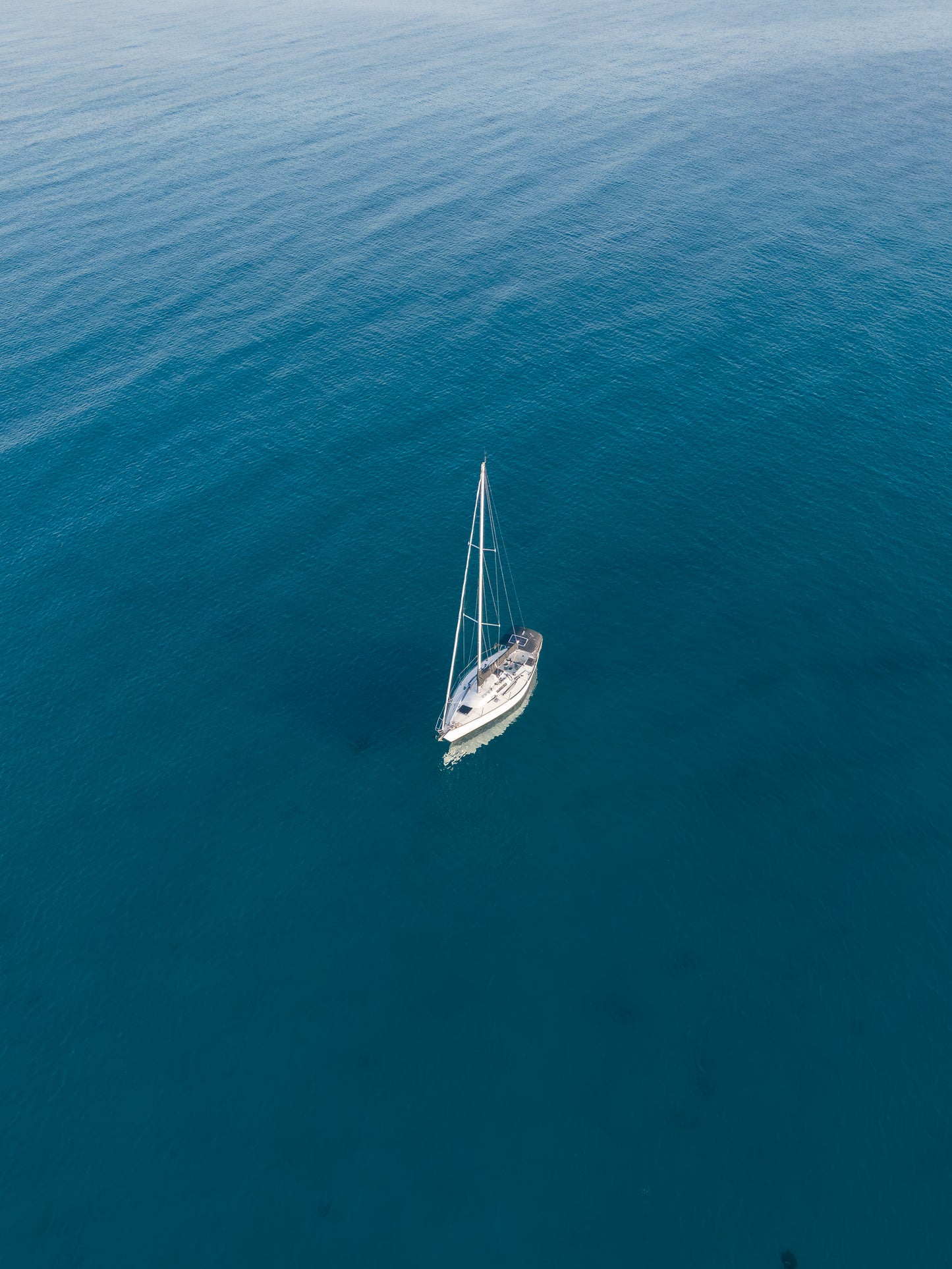 Sailboat in the middle of a vast blue ocean. Adrift — lone sailboat aerial fine art print, ocean wall art by Aqua Visions Photography