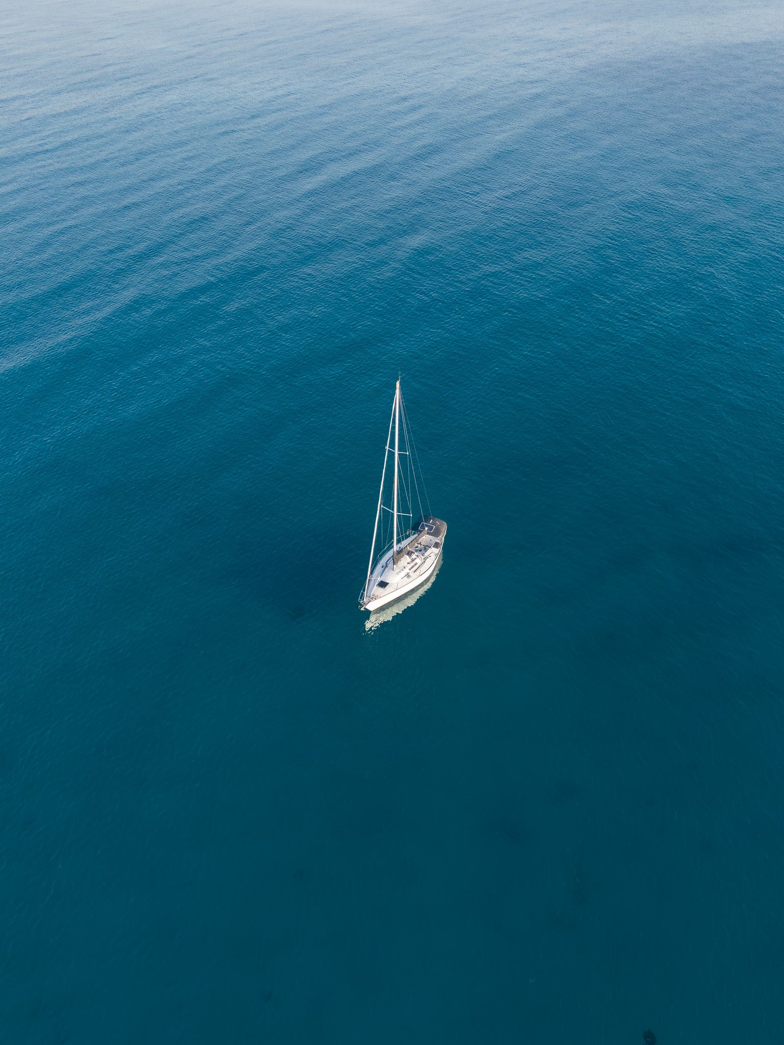 Sailboat in the middle of a vast blue ocean. Adrift — lone sailboat aerial fine art print, ocean wall art by Aqua Visions Photography